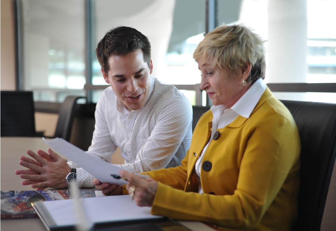 Man and woman in business attire looking at a piece of paper.