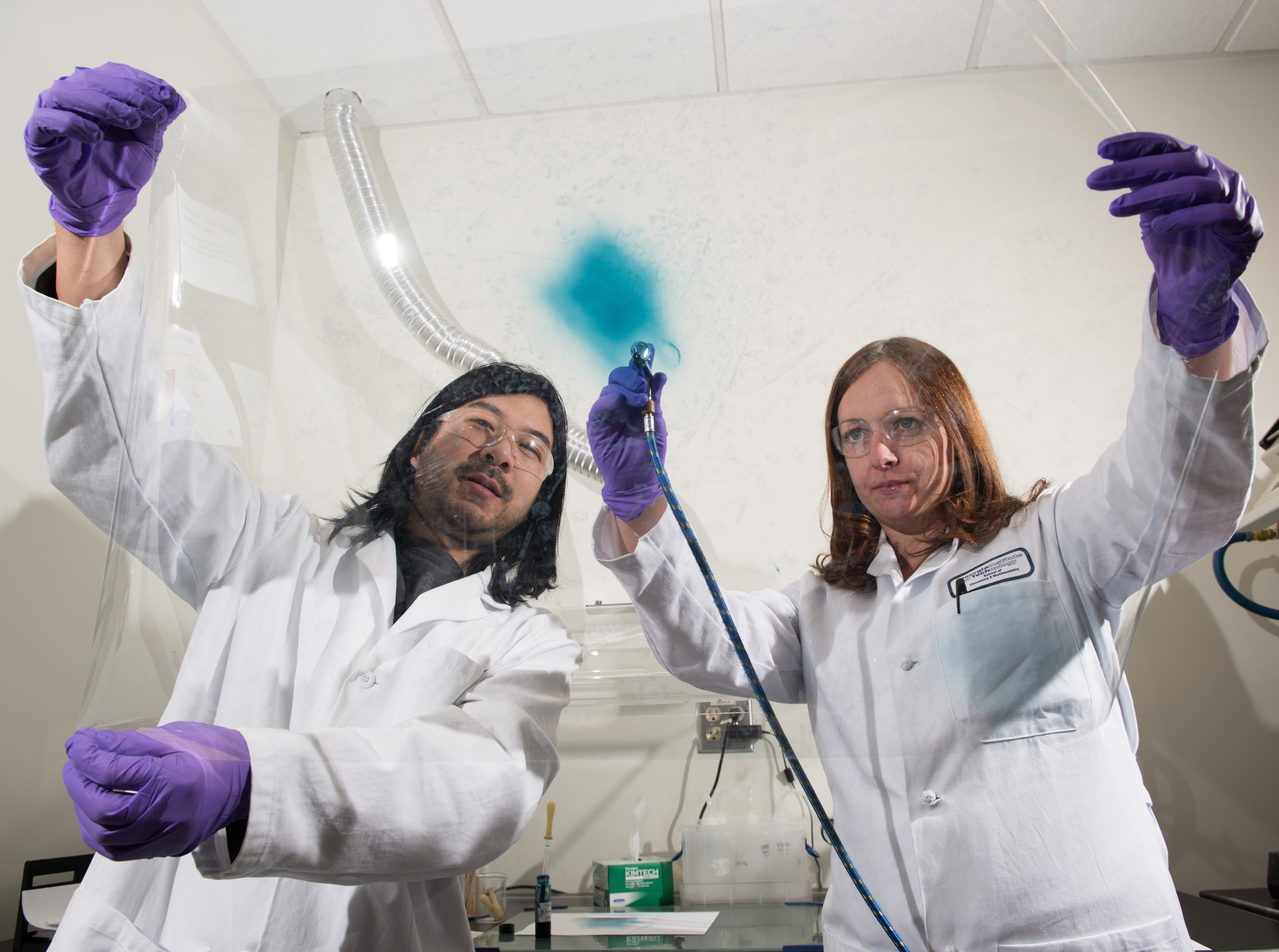 Georgia Tech researchers Eric Shen and Anna Osterholm demonstrate how films of electrochromic polymers can be applied to large surfaces. (Credit: Rob Felt)